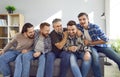 Male bearded friends sitting on sofa at home, smiling and having fun.