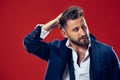 Male beauty concept. Portrait of a fashionable young man with stylish haircut wearing trendy suit posing over red Royalty Free Stock Photo