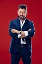 Male beauty concept. Portrait of a fashionable young man with stylish haircut wearing trendy suit posing over red Royalty Free Stock Photo