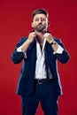 Male beauty concept. Portrait of a fashionable young man with stylish haircut wearing trendy suit posing over red Royalty Free Stock Photo