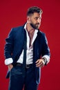 Male beauty concept. Portrait of a fashionable young man with stylish haircut wearing trendy suit posing over red Royalty Free Stock Photo