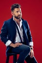 Male beauty concept. Portrait of a fashionable young man with stylish haircut wearing trendy suit posing over red Royalty Free Stock Photo