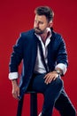 Male beauty concept. Portrait of a fashionable young man with stylish haircut wearing trendy suit posing over red Royalty Free Stock Photo