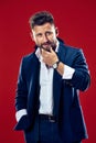 Male beauty concept. Portrait of a fashionable young man with stylish haircut wearing trendy suit posing over red Royalty Free Stock Photo