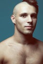 Male beauty concept. Portrait of handsome muscular male model posing over blue background. Half-shaved head and healthy clean skin Royalty Free Stock Photo