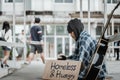 Male beggar in hood showing seeking human kindness sign on cardboard Royalty Free Stock Photo