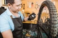 male bicycle mechanic in apron holding bottle while applying lubricant spray