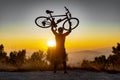 Male biker holds bike above head