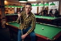 Male billiard player with cue poses at the table