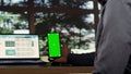 Male billionaire uses greenscreen phone display at desk