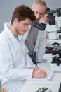 male biology teacher looking through microscope in classroom Royalty Free Stock Photo