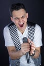 Male black-haired rock singer performs singing to microphone