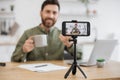 Male blogger holding cup and talking with followers at home