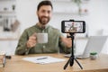 Male blogger holding cup and talking with followers at home