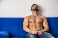 Male bodybuilder listening to music on sofa Royalty Free Stock Photo