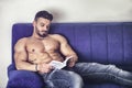 Male bodybuilder reading book on sofa Royalty Free Stock Photo