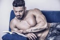 Male bodybuilder reading book on sofa Royalty Free Stock Photo