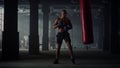 Man hitting punch bag during intense workout. Male boxer practicing kickboxing Royalty Free Stock Photo