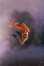 Male breakdancer jumps off high in the air while performing a cool dance move, a lot of smoke in the background Royalty Free Stock Photo