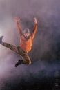 Male break-dancer jumps off high in the air while performing a cool dance move, a lot of smoke in the background Royalty Free Stock Photo