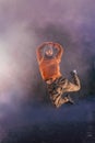 Male breakdancer jumps off high in the air while performing a cool dance move, a lot of smoke in the background Royalty Free Stock Photo