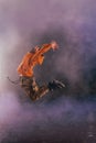 Male breakdancer jumps off high in the air while performing a cool dance move, a lot of smoke in the background Royalty Free Stock Photo