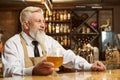 Male brewer standing over bar and smiling