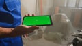 Male builder in blue overalls is holding smartphone with green screen chroma key. Buying building materials online Royalty Free Stock Photo