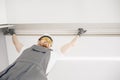 Male builder carpenter installs curtain on ceiling, bottom view Royalty Free Stock Photo