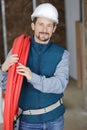 male builder carrying reel red pipe