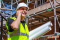 Male Builder Construction Worker on Building Site Using Cell Phone and Plans Royalty Free Stock Photo