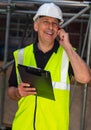 Male Builder Foreman Architect Contractor on Building Site Using Phone and Plans Royalty Free Stock Photo