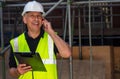 Male Builder Foreman Architect Contractor on Building Site Using Phone and Plans