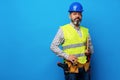 Male builder or handyman in uniform holding clipboard against blue background Royalty Free Stock Photo