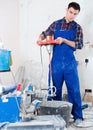 Builder mixing plaster in bucket with electric mixer