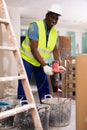 Male builder mixing plaster in bucket using electric mixer closeup