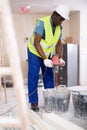 Male builder mixing plaster in bucket using electric mixer closeup