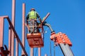 Male builders work at height in a lifting cradle, creating the iron frame of the building