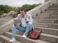 Employee with tablet and talking on a phone, sitting on the urban background. Technology progress concept. Copy space.