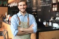 Male business owner behind the counter of a coffee shop with crossed arms, looking at camera Royalty Free Stock Photo