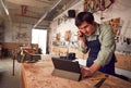 Male Business Owner In Workshop Using Digital Tablet And Making Call On Mobile Phone Royalty Free Stock Photo