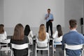 Male business trainer giving lecture in room with projection screen