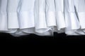 Male business wardrobe many clean white shirt sleeve hanging isolated on black background