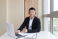 Male businessman conducts online training using a headset and laptop, sits in a stylish office by the window