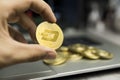 Male businessman hand holding Dash coin on a background of laptop keyboard and pile of golden coins. Virtual money and