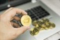 Male businessman hand holding Dash coin on a background of laptop keyboard and pile of golden coins. Virtual money and