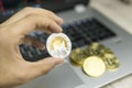 Male businessman hand holding Monero coin on a background of laptop keyboard and pile of golden coins. Virtual money and