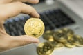 Male businessman hand holding Ripple coin on a background of laptop keyboard and pile of golden coins. Virtual money and