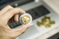 Male businessman hand holding Ripple coin on a background of laptop keyboard and pile of golden coins. Virtual money and