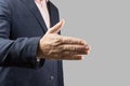 Male businessman holds out his hand for a handshake on a gray background. Cropped, no head. Businessman and gesture concept Royalty Free Stock Photo